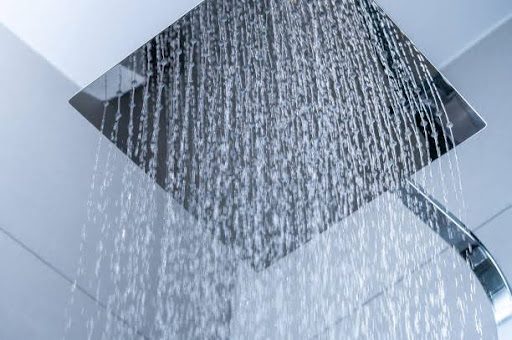Low angle view of water flowing from shower head in bathroom.